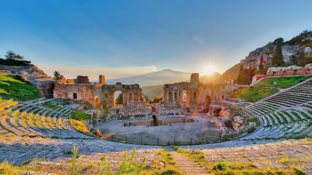 Ancient theatre of Taormina with Etna erupting volcano at sunset